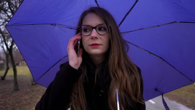 Junge-Frau-mit-Regenschirm-mit-Smartphone