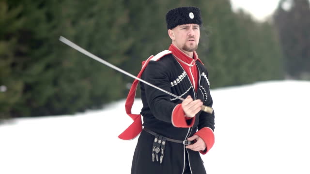 Un-joven-con-ropa-cosaca-balanceando-una-espada-en-un-paisaje-invernal-en-la-nieve.