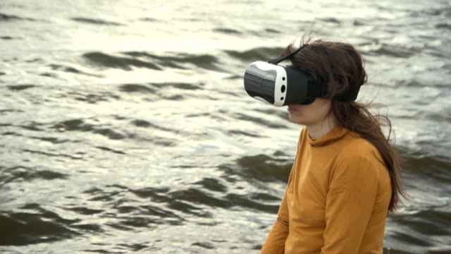 Eine-junge-Frau-nutzt-virtual-Reality-Brille-neben-starken-Wellen.