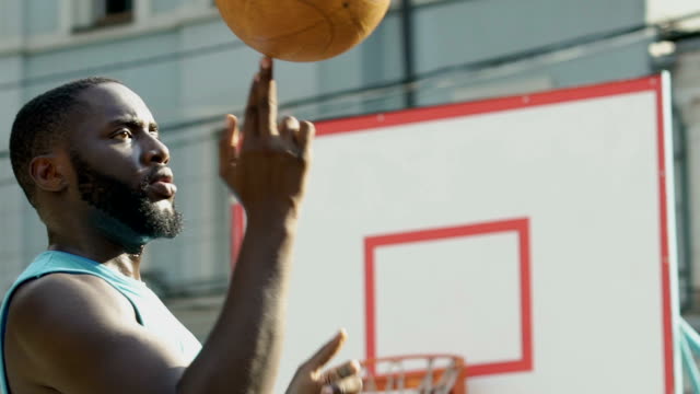 Beginner-basketball-player-spinning-ball-on-finger,-making-tricks-before-game