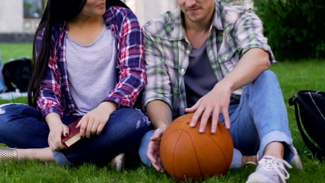 Male-and-female-students-sitting-on-lawn-closely,-having-conversation,-flirting