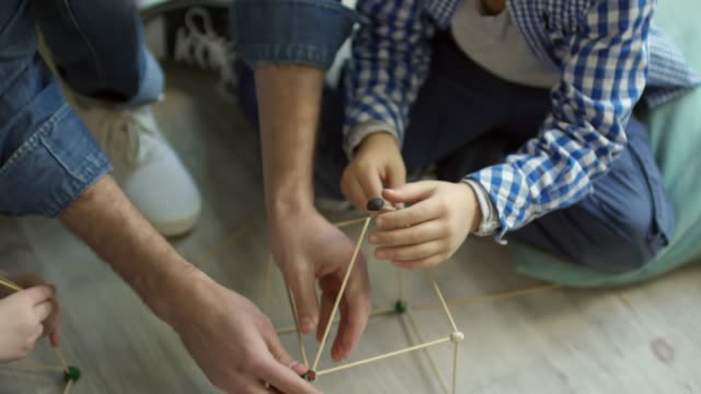Teacher-and-Little-Boy-Making-House-with-Wooden-Sticks