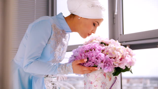Muslim-bride-in-blue-wedding-dress-for-nikah,-smelling-flowers