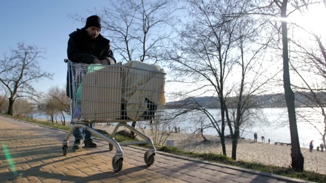 Front-view-of-homeless-mature-man-pushing-cart
