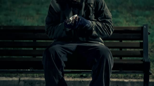 Einsame-Obdachlosen-im-Park-in-der-Nacht,-zählt-sein-Geld-um-etwas-zu-essen-kaufen