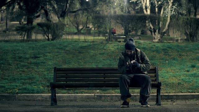 homeless-man--bench-counting-coins-in-a-city-park