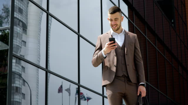 Businessman-using-his-smart-phone.-Handsome-young-man-communicating-on-smartphone-smiling-confident