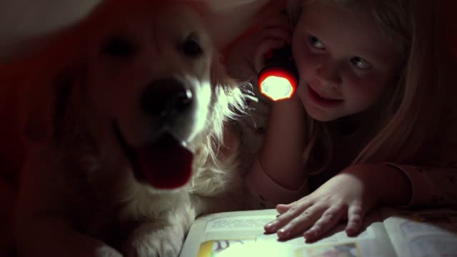 vida-feliz-con-los-animales-domésticos---los-niños-por-la-noche-leyendo-un-libro-debajo-de-las-cobijas-con-su-perro-grande