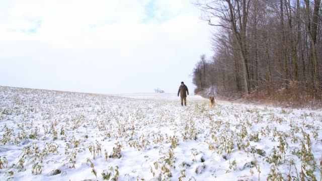 Un-hombre-maduro-cincuentón-paseando-su-perro-en-una-mañana-de-invierno-cubierto-de-nieve-hermosa.