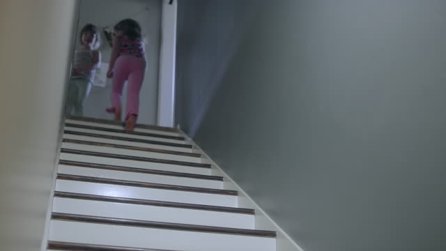 A-girl-runs-up-a-set-of-stairs-and-a-dog-runs-up-after-her