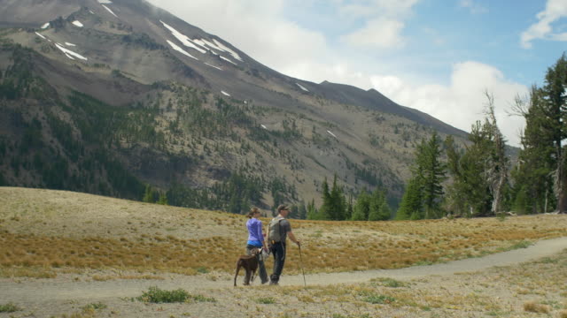 Two-hikers-and-their-dog-walk-together