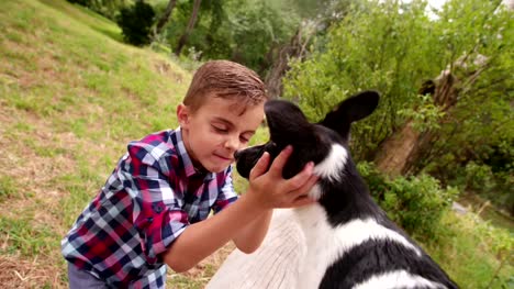 Little-boy-hugging-and-stroking-his-puppy-dog-in-park