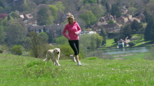 Mujer-madura-con-perro-a-correr-por-el-campo-de-tiro-en-R3D