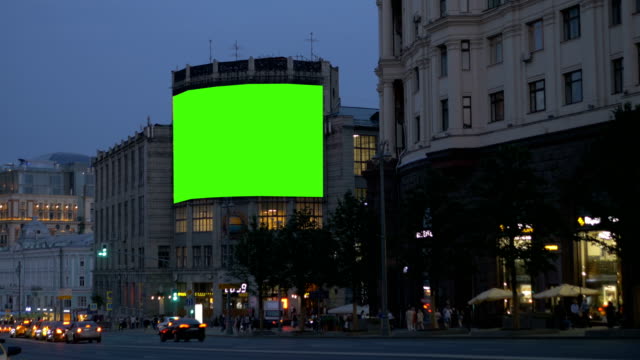 A-large-billboard,-on-an-ancient-building,-on-a-busy-street.-Green-screen.