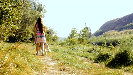Eine-junge-Frau-ist-mit-einem-Husky-im-Wald-spazieren.