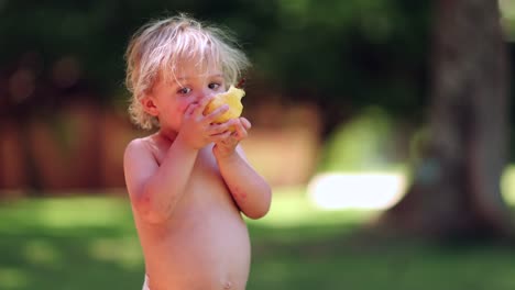 Cándido-retrato-de-muchacho-infantil-comer-fruta-al-aire-libre-en-4-k-clip-de-resolución