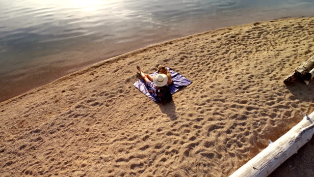Frau-mit-ihrem-Hund-sitzen-nahe-der-Küste,-Fluss-an-einem-sonnigen-Tag-4K-4k