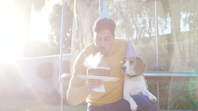 Hombre-joven-celebrando-cumpleaños-de-perro-de-animal-doméstico-en-jardín-4K-4k