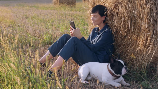 Mädchen-mit-Hund-ruht-messaging-auf-Smartphone-im-Freien.