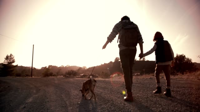 Joven-padre-y-su-hijo-caminando-por-sendero-de-montaña-con-perro