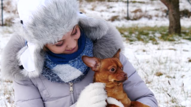Frau-spielt-mit-ihren-kleinen-Hund-draußen-winter