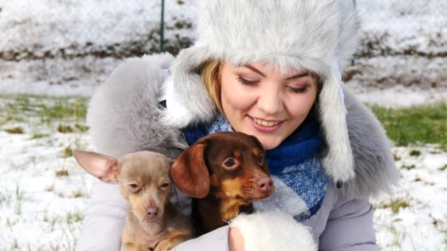 Frau-spielt-mit-ihren-kleinen-Hunden-draußen-winter