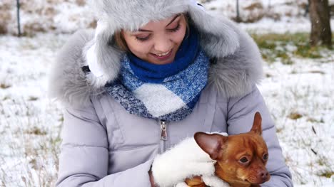 Frau-spielt-mit-ihren-kleinen-Hund-draußen-winter