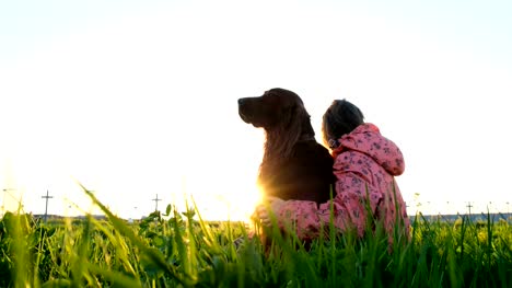 Mujer-abrazando-a-un-perro-en-la-puesta-de-sol,-una-chica-joven-con-un-animal-doméstico-sentado-sobre-la-hierba-y-relajante-en-la-naturaleza
