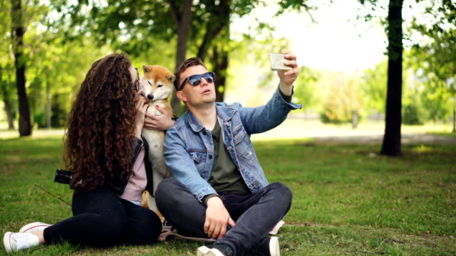 Popular-blogger-is-recording-video-about-himself,-his-wife-and-cute-dog,-man-is-holding-smartphone,-talking-and-looking-at-camera-then-on-the-woman-and-animal.