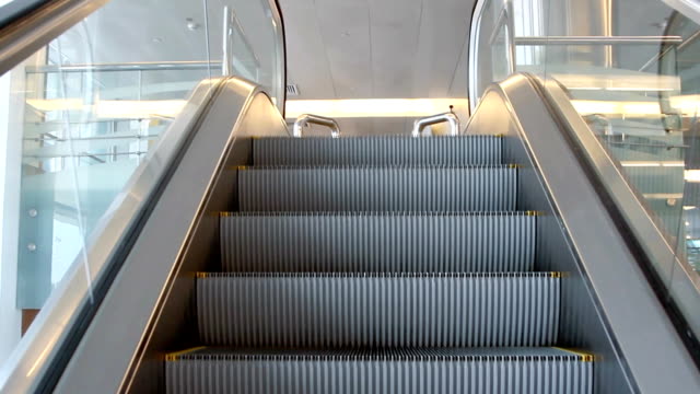 Empty-escalator-stairs-moving-up-with-logo-warning-in-modern-office-building