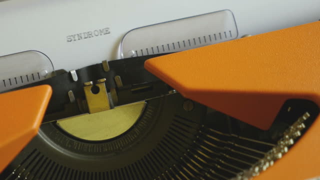 Close-up-footage-of-a-person-writing-SYNDROME-on-an-old-typewriter,-with-sound