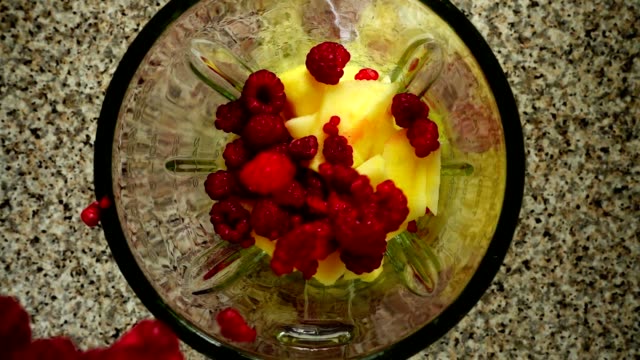 Raspberry-falls-in-a-blender-bowl-on-pieces-of-apples.-Slow-motion.	Shooting-in-kitchen.-Top-view.