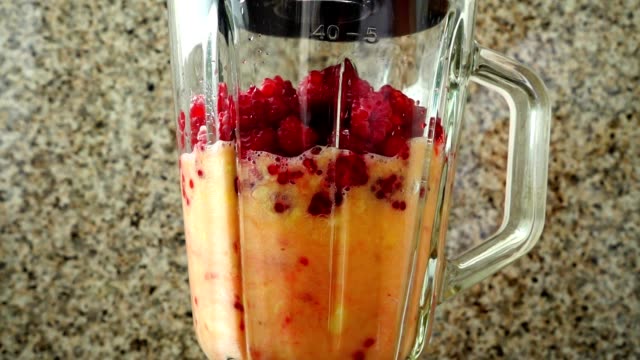 Preparation-of-cocktail-in-the-blender-from-apples,-bananas-and-raspberry.	Slow-motion.