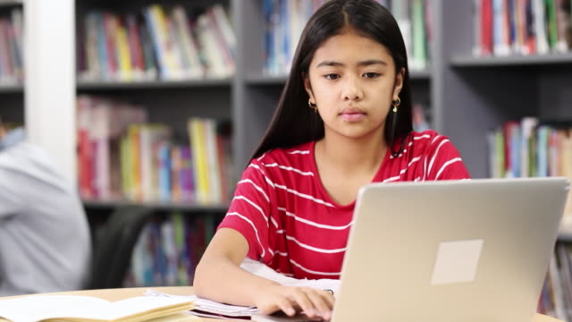 Weibliche-High-School-Schüler-arbeiten-am-Laptop-In-der-Bibliothek