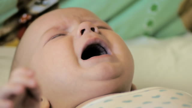 Close-up-of-a-newborn-boy-crying-lying-in-his-crib,-in-slow-motion.