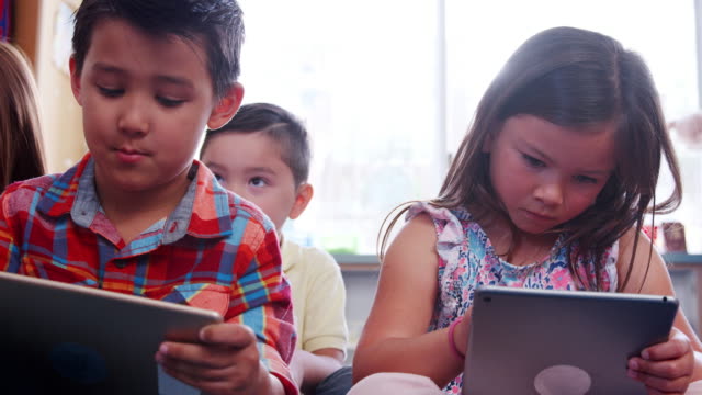 Tres-alumnos-utilizando-tabletas-durante-la-lección-en-la-escuela