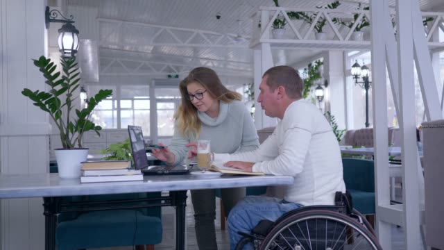 erfolgreiche-Menschen-mit-Behinderungen,-kreative-freier-Unternehmer-im-Rollstuhl-mit-Frau-diskutieren-Startup-Unternehmen-mit-Laptop-computer
