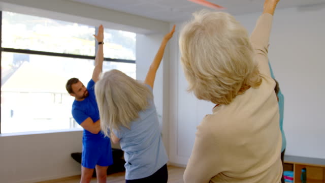 Entrenador-de-asistencia-a-senior-femenino-en-la-realización-de-yoga-4k