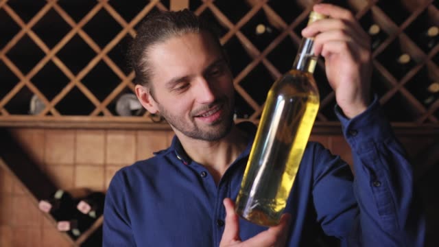 Smiling-Man-With-Bottle-Of-Wine-In-Cellar-At-Winery-Restaurant