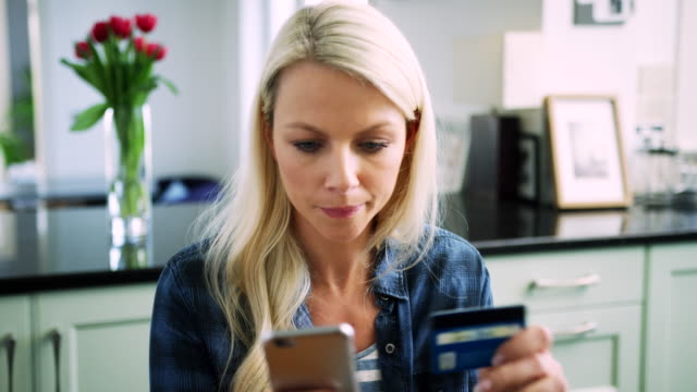 Beautiful-Blond-Woman-Typing-Credit-Card-Details-Into-Smart-Phone