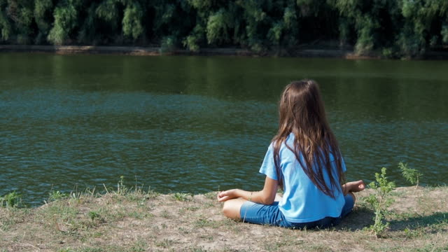 Das-Mädchen-ist-am-Ufer-Flusses-meditieren.