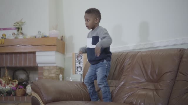 Afro-americano-pequeño-niño-lindo-saltando-en-el-sofá