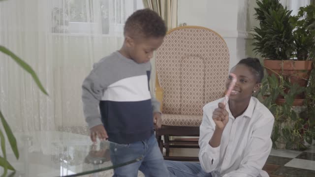 Zuversichtlich-schöne-afrikanische-Amerikanerin,-die-mit-ihrem-kleinen-lustigen-Sohn-spielt