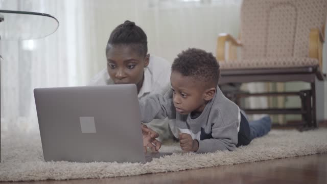 Afrikanische-Amerikanerin-mit-ihrem-niedlichen-Sohn-schaut-auf-den-Laptop.
