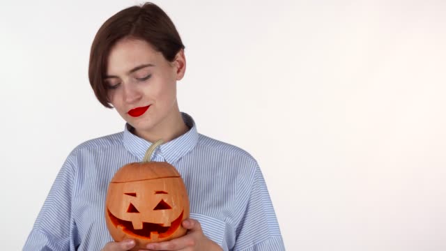 Mujer-feliz-mostrando-los-pulgares-hacia-arriba,-sosteniendo-Halloween-calabaza-tallada