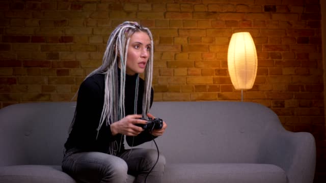 Closeup-shoot-of-young-attractive-caucasian-hipster-female-playing-video-games-on-TV-and-failing-a-level-sitting-on-the-couch-indoors-in-a-cozy-apartment