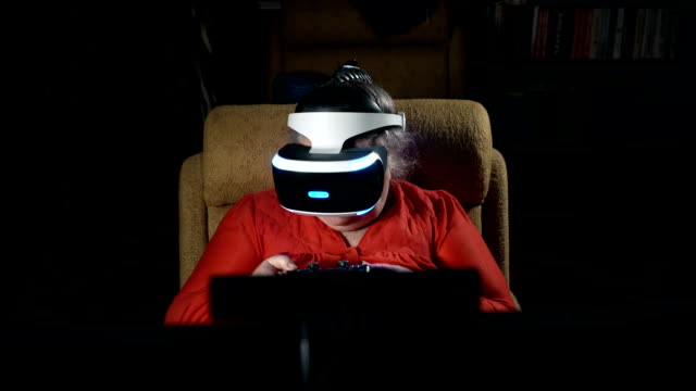 70-year-old-woman-playing-video-game-uses-VR-headset-and-gaming-controller