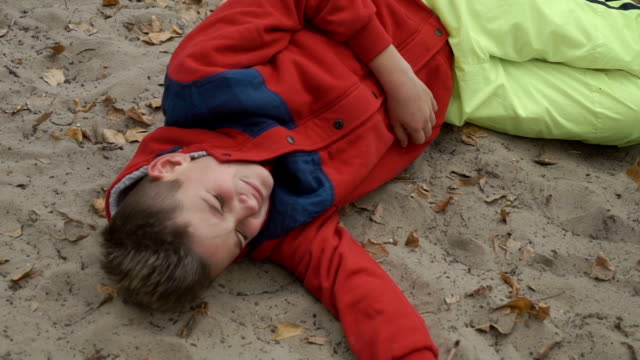 Little-crying-boy-lays-on-sand