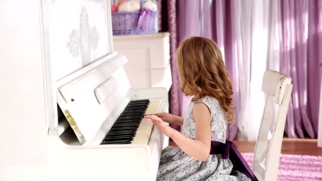 chica-rubia-juega-piano,-muchacha-en-un-vestido-con-un-cinturón-púrpura,-de-movimiento-lento.