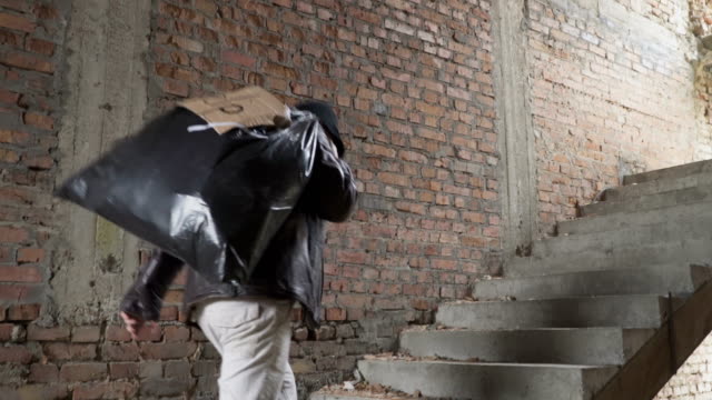 Homeless-up-stairs-with-garbage-bag-behind-his-back